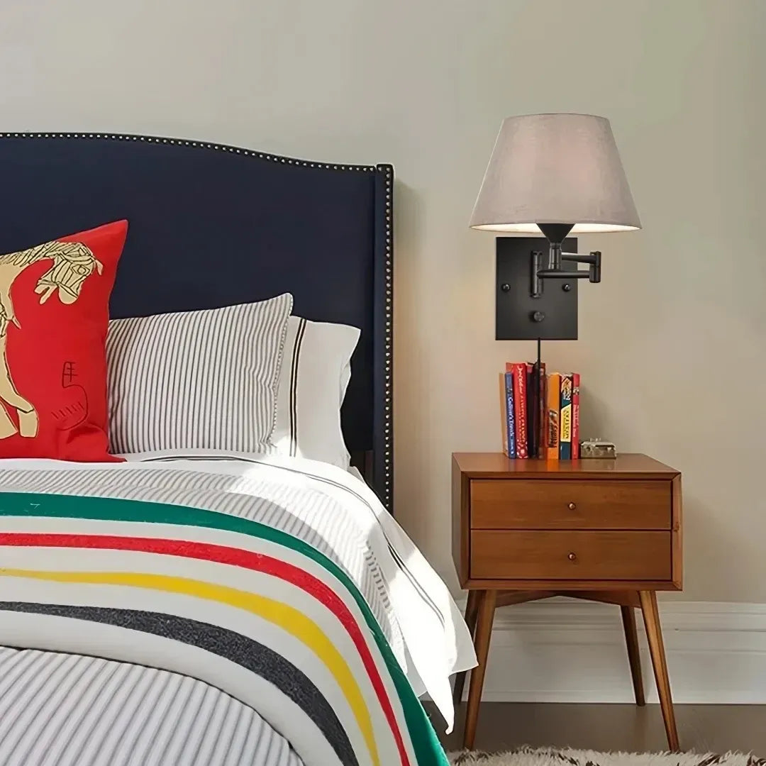 Moderne Wandlampe mit Stoffschirm neben einem Bett