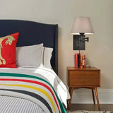 Moderne Wandlampe mit Stoffschirm neben einem Bett